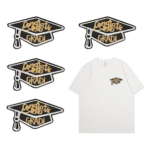 Könnte beinhalten: Vier schwarze Abzeichen in Form von Abschlusskappen mit goldener Stickerei, auf denen "Congrats Gradi" steht. Die Abzeichen sind auf einem weißen T-Shirt abgebildet.