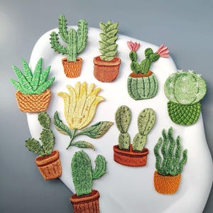 May include: Embroidered patches featuring various cactus and succulent designs in terracotta pots. The patches showcase detailed stitching in shades of green, yellow, and pink, creating a textured, three-dimensional effect. The collection includes different cactus shapes and a yellow flower.