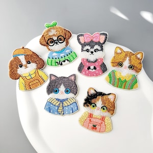May include: A collection of six embroidered patches featuring stylized cats and dogs wearing colorful clothing. The designs include animals in sweaters, overalls, and dresses with detailed textures, vibrant thread colors, and distinct facial expressions.