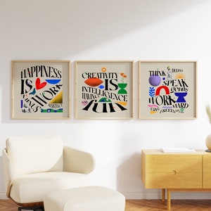 May include: Three framed motivational posters with colorful abstract designs and text. The posters are hung on a white wall. The text on the posters reads "Happiness is work minus resistance", "Creativity is intelligence having fun", and "Think deeply, speak gently, work hard, give freely, and be kind".