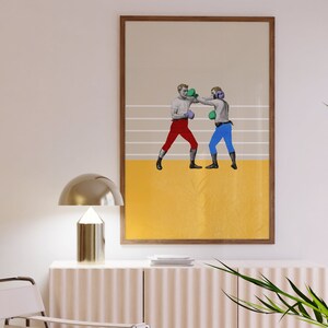 Peut inclure: Une impression encadr&eacute;e de deux boxeurs dans un ring de boxe. Les boxeurs portent des shorts et des gants rouges et bleus. L'arri&egrave;re-plan est jaune avec des lignes blanches.