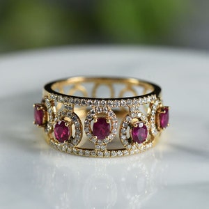 Puede incluir: Un anillo de oro con una banda de pequeños diamantes y cinco rubíes engastados en círculos. Las piedras de rubí son de color rojo intenso.