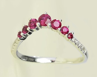Puede incluir: Un anillo de banda de plata con una fila curva de piedras preciosas rojas y pequeñas piedras blancas.