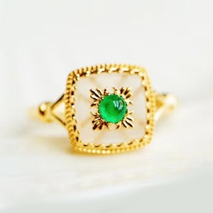 May include: A gold ring with a square-shaped setting featuring a white stone and a green gemstone in the center.