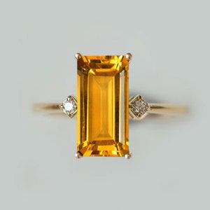 May include: A gold ring with a large, rectangular, yellow citrine gemstone and two smaller, round, white diamonds.
