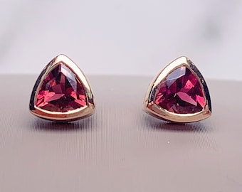 May include: A pair of gold earrings with triangular red gemstones.