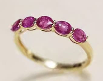 Puede incluir: Un anillo de banda de oro con seis piedras preciosas de rubí de forma ovalada.