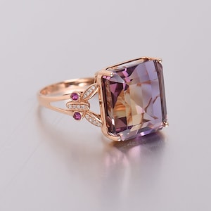 Puede incluir: Un anillo de oro rosa con una gran amatista de forma cuadrada. El anillo presenta un diseño de mariposa con pequeños diamantes y detalles de rubí.