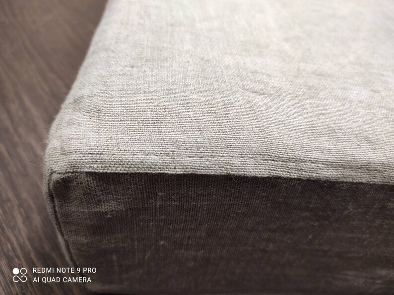 Puede incluir: Primer plano de un coj&iacute;n de lino beige con un tejido beige ligeramente m&aacute;s oscuro en el borde inferior.