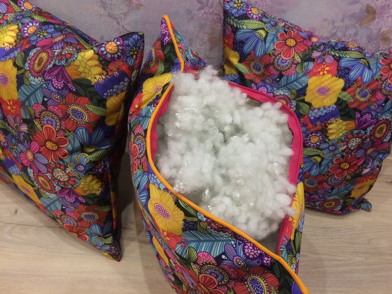 K&ouml;nnte beinhalten: Drei farbenfrohe Kissenbez&uuml;ge mit einem Blumenmuster. Die Kissenbez&uuml;ge sind ge&ouml;ffnet, um die wei&szlig;e F&uuml;llung im Inneren zu zeigen.