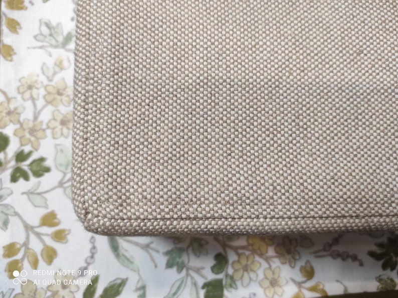 May include: Close-up of a beige fabric with a woven texture. The fabric has a subtle sheen and a slightly rough feel.