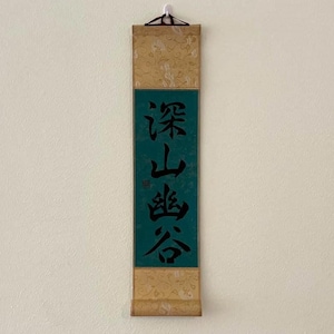 Peut inclure: Un rouleau vert et or avec une calligraphie chinoise noire qui lit "深山含秀".