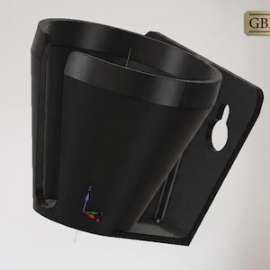 May include: A black wall-mounted cup holder with a unique design. The holder features a curved cup-shaped receptacle and a flat back panel with a keyhole for hanging. The GBL Gifts logo is visible in the top right corner.