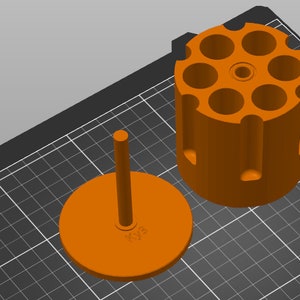 May include: Orange plastic revolver bullet holder with a removable lid. The holder has six slots for bullets.