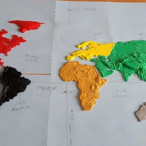 May include: A 3D printed world map with continents in different colors. North America is red, South America is black, Europe is yellow, Asia is green, Africa is orange, and Australia is gray. The map is labeled with the names of the continents and oceans.