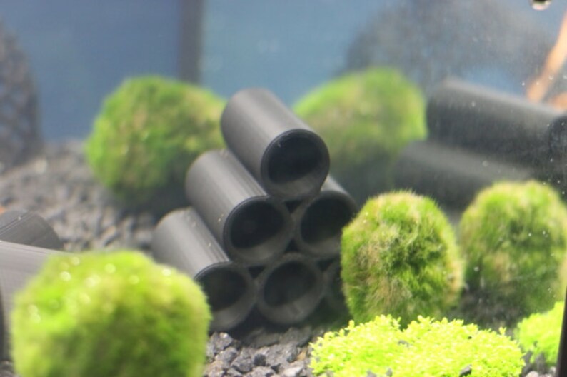 Pode incluir: Caverna de aqu&aacute;rio de cer&acirc;mica preta com seis aberturas, empilhadas em forma de pir&acirc;mide. A caverna &eacute; cercada por bolas de musgo verde e cascalho.
