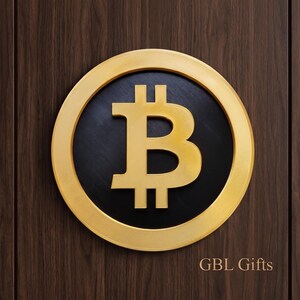 May include: A gold-colored Bitcoin symbol inside a black circle, set against a dark wood background. The Bitcoin symbol is in the center of the circle, with the text "GBL Gifts" at the bottom right.