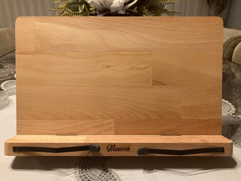 May include: A wooden book stand with a black metal page holder. The stand is engraved with the name "Maureen".