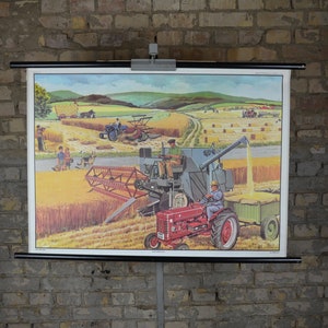 Peut inclure: Une affiche éducative vintage représentant un tracteur rouge tirant une moissonneuse-batteuse dans un champ de blé. L'affiche est montée sur un rouleau et a un cadre noir.