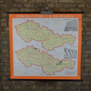 May include: A vintage map of Czechoslovakia from 1945-1980, highlighting cultural aspects. The map is printed on a white background with orange borders and features a grid pattern. The map shows the country's regions and includes illustrations of buildings and a dam.