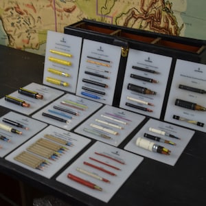 Könnte beinhalten: Eine Sammlung verschiedener Arten von elektrischen Kabeln und Drähten, die auf weißen Karten präsentiert werden. Die Karten sind mit der Art des Kabels beschriftet und in einer Holzkiste angeordnet.