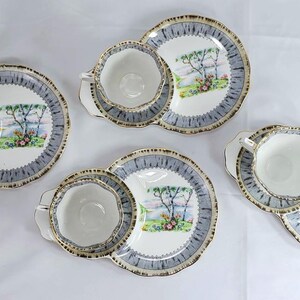 Puede incluir: Cuatro juegos de tazas y platillos. Cada juego incluye una taza blanca con borde dorado, un platillo a juego y un plato peque&ntilde;o. Los platos y platillos tienen un borde azul y gris y una escena de paisaje en el centro.