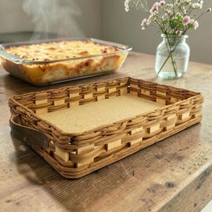 Peut inclure: Un plateau rectangulaire en osier tressé avec des parois brun clair, une base plate beige et une poignée latérale en cuir brun foncé. Le plateau présente une ouverture sur le dessus et une structure tressée avec des motifs verticaux et horizontaux.