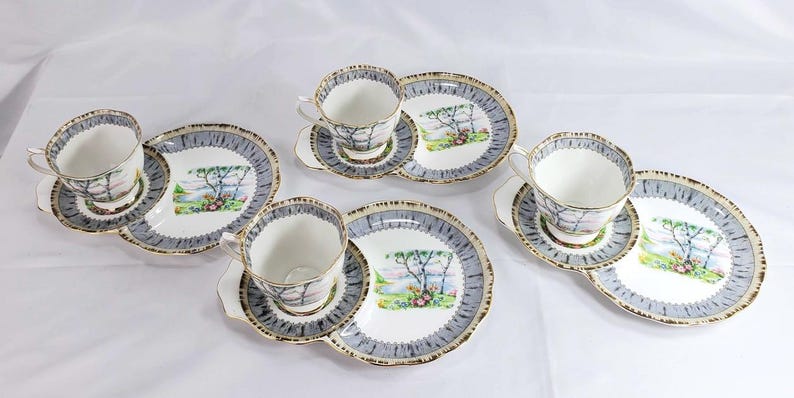 Puede incluir: Juego de t&eacute; vintage con seis tazas, platillos y platos. Cada pieza presenta un paisaje con un &aacute;rbol y un borde azul y dorado. Ideal para disfrutar de una buena taza de t&eacute;.