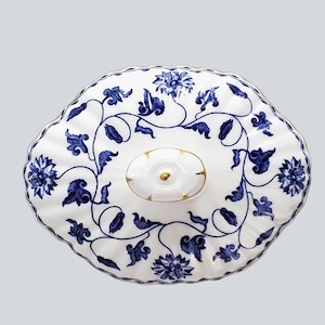 May include: A white porcelain serving dish with a blue floral pattern. The dish has a scalloped edge and a lid with a gold knob. The blue floral design includes flowers and vines. The dish is likely used for serving food.