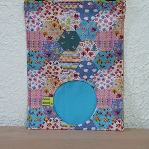 May include: A colorful fabric pouch with a hexagonal patchwork design featuring a variety of floral and woodland patterns. The pouch has a circular opening and a turquoise lining. The text "odos labonds" is printed on the front of the pouch.