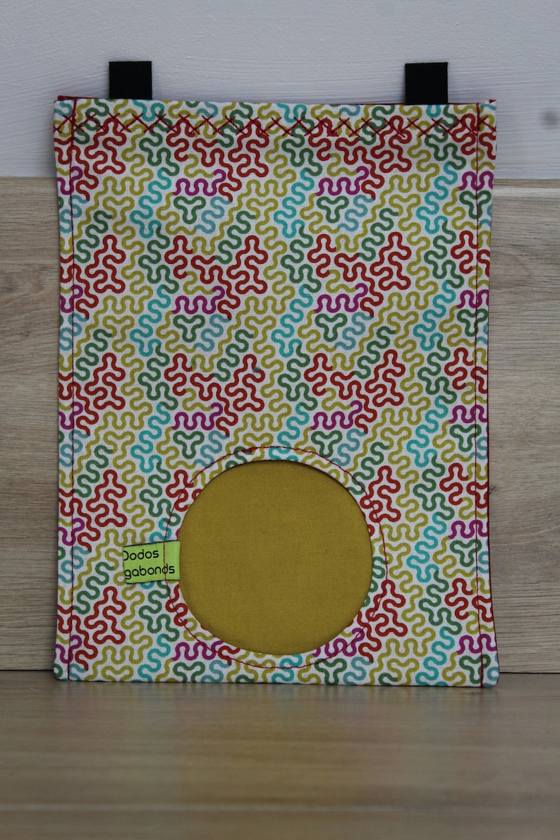 May include: A white fabric bag with a colorful geometric pattern and a round opening. The bag has a green label that says "Dodos gabonds".