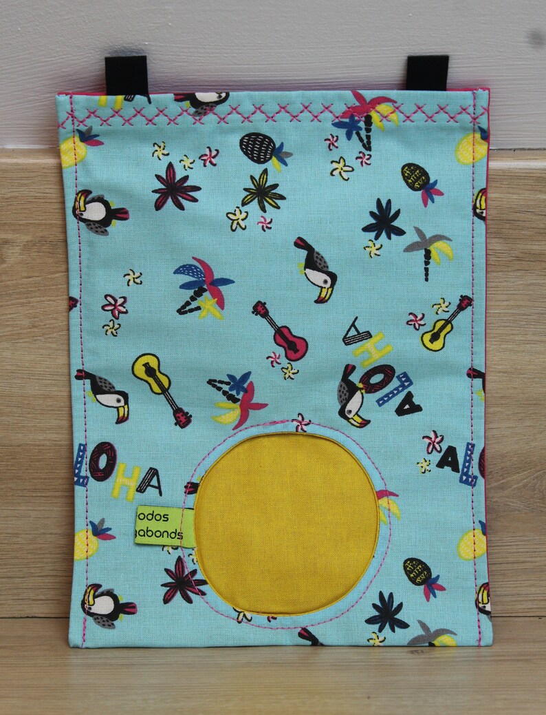 May include: A blue fabric storage bag with a yellow circle in the center. The bag has a tropical print with toucans, palm trees, pineapples, flowers, and guitars. The text "ALOHA" is printed on the bag.