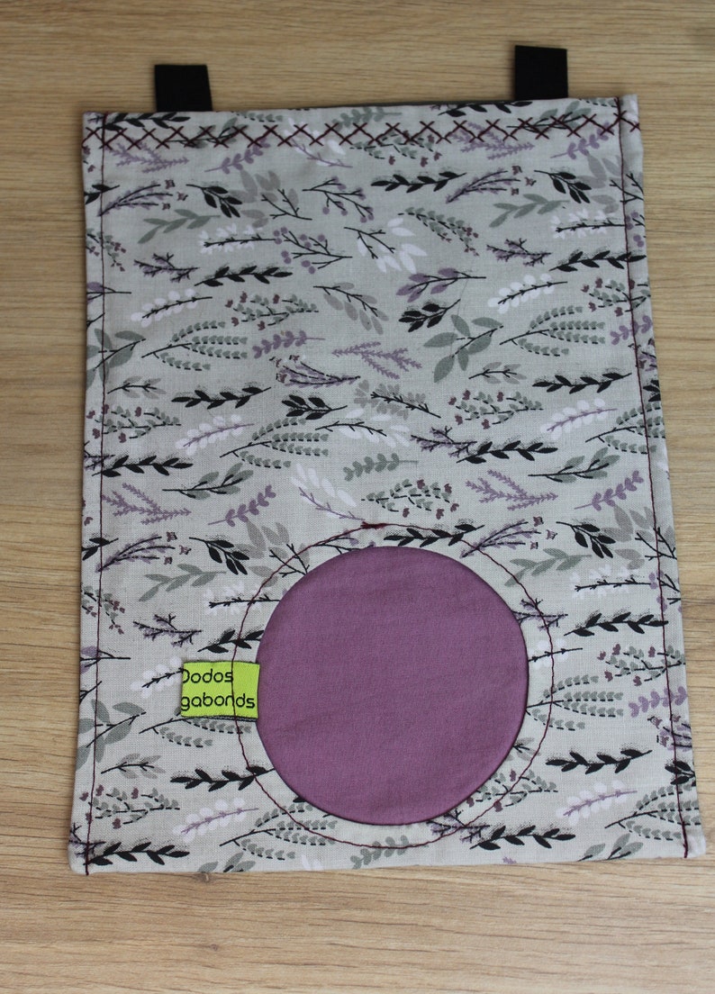 May include: A gray fabric pouch with a purple circle in the center. The pouch has a floral pattern with black and white leaves and a green label that says "Dodos gobands".