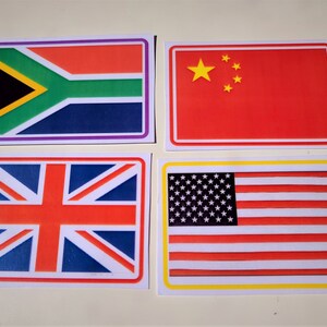 Puede incluir: Cuatro banderas rectangulares con bordes blancos. Las banderas son las de Sud&aacute;frica, China, el Reino Unido y los Estados Unidos. Las banderas est&aacute;n sobre una superficie blanca.