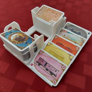 Bandeja de cartas para el juego de mesa Ticket to Ride, con billetes de destino, cartas de tren, pila de descarte y cartas boca arriba.