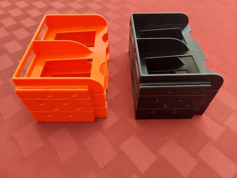 May include: Two 3D printed storage organizers, one orange and one black, with multiple compartments. The organizers are stacked on top of each other.