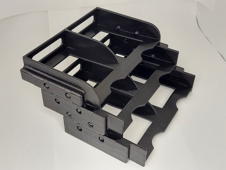 May include: Black plastic organizer with multiple compartments, designed to hold small items. The organizer is made of two stacked levels, each with several slots.