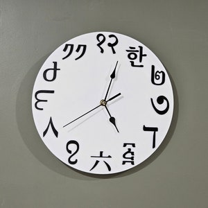 Op de afbeelding: Een witte klok met zwarte wijzers en zwarte cijfers. De cijfers zijn in het Koreaans.