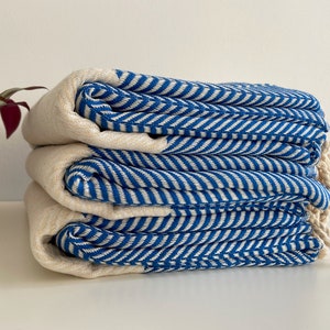 May include: A stack of four blue and white striped towels. The towels are folded and have a fringe on the ends.
