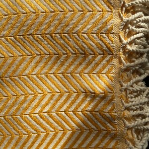 May include: A yellow and white throw blanket with a chevron pattern and fringe on the edges.