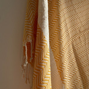 May include: A yellow and white striped throw blanket with fringe. The blanket is made of a soft, woven fabric.