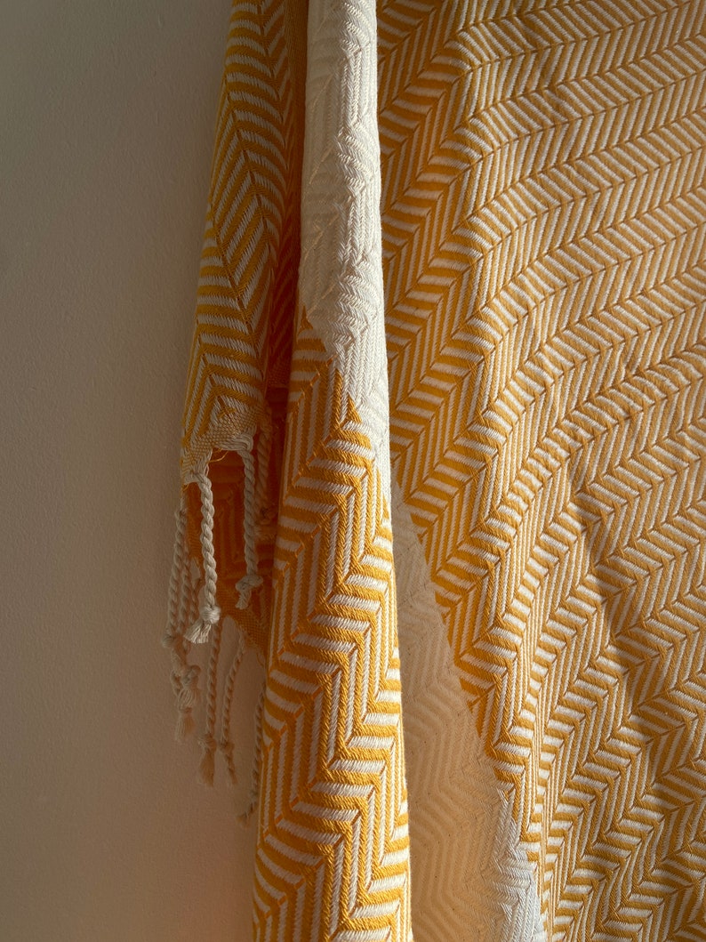 May include: A yellow and white striped throw blanket with fringe. The blanket is made of a soft, woven fabric.