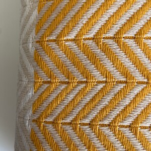 May include: Close-up of a yellow and white woven fabric with a chevron pattern.