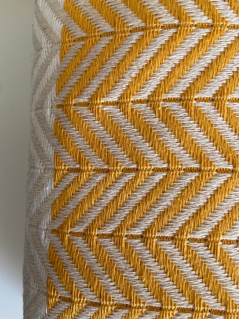 May include: Close-up of a yellow and white woven fabric with a chevron pattern.