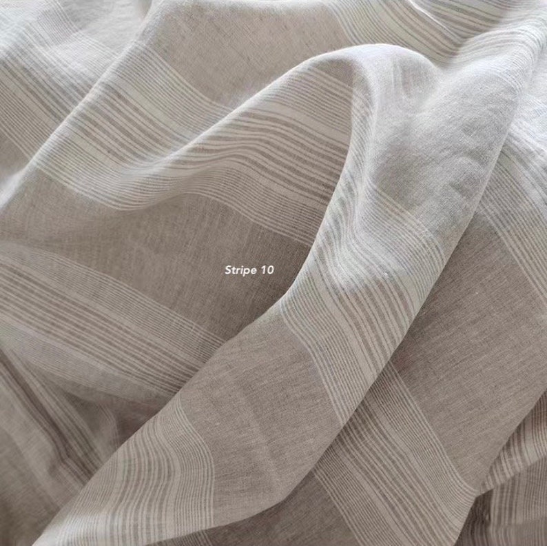 Puede incluir: Primer plano de una tela a rayas de color marr&oacute;n claro y blanco. La tela est&aacute; tejida con una textura sutil y tiene una sensaci&oacute;n suave y fluida. La tela est&aacute; etiquetada como "Stripe 10".