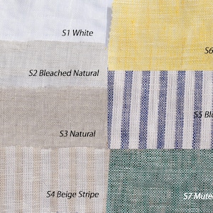 Puede incluir: Una exhibición de muestras de tela de lino con siete colores diferentes. Los colores incluyen blanco, natural blanqueado, natural, beige a rayas, dorado, azul a rayas y verde apagado. Cada muestra está etiquetada con su nombre de color.