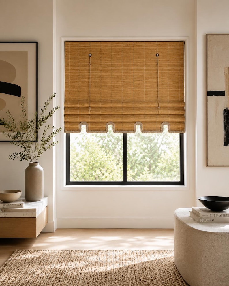 May include: A woven bamboo roman shade with a light brown finish, featuring a scalloped bottom edge with a light-colored trim. The shade is suspended by two thin cords attached to circular hardware at the top, covering a rectangular window frame.