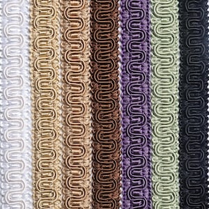 May include: A collection of seven vertical strips of gimp braid trim arranged side by side. The colors include white, light gold, medium gold, dark brown, purple, sage green, and black. Each strip features a consistent, repeating serpentine pattern.
