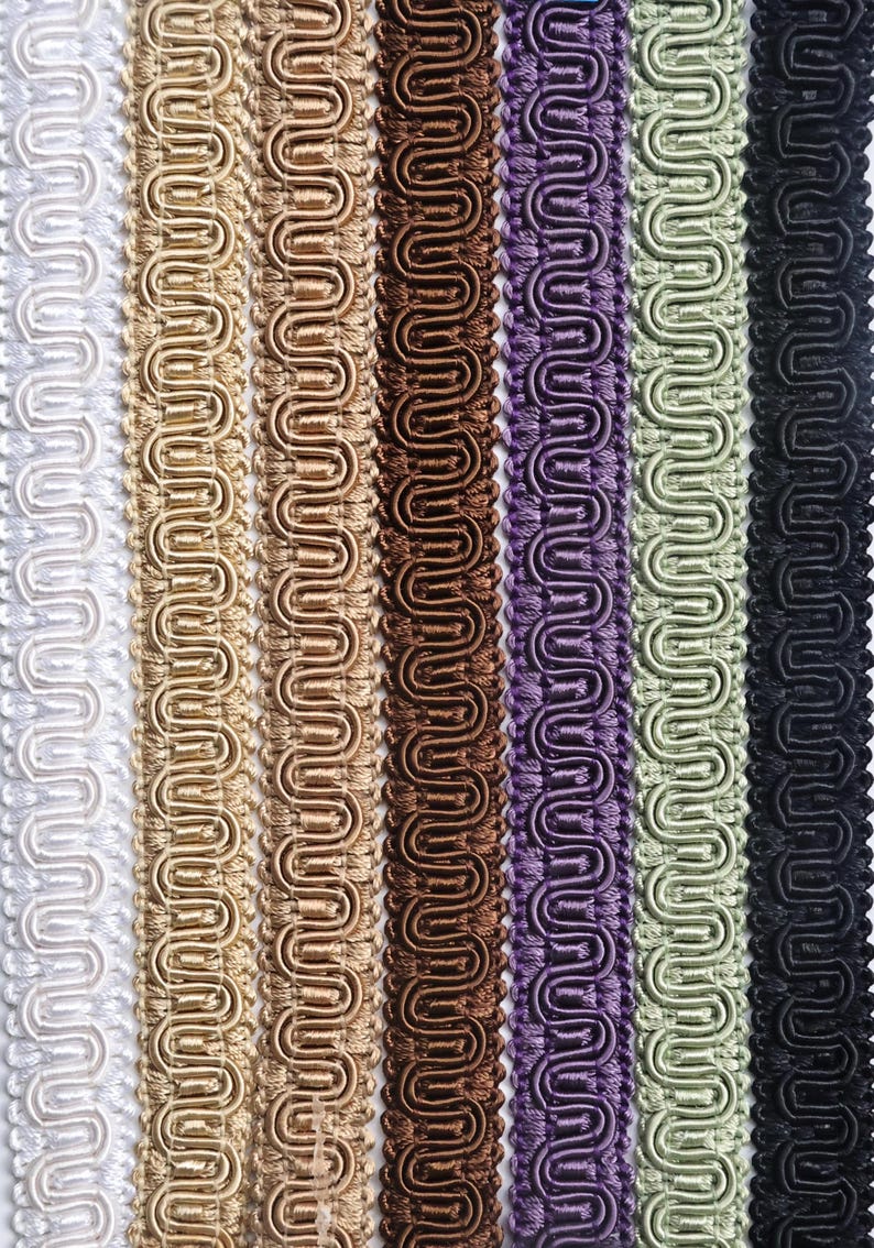 May include: A collection of seven vertical strips of gimp braid trim arranged side by side. The colors include white, light gold, medium gold, dark brown, purple, sage green, and black. Each strip features a consistent, repeating serpentine pattern.