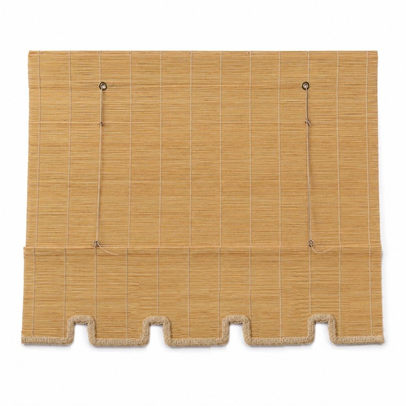 May include: A rectangular bamboo window shade in a light tan color, featuring a woven texture with vertical stitching. The bottom edge has a scalloped design finished with a thick, light-colored braided trim and two thin pull cords attached.